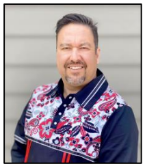 A man wearing a colorful shirt standing in front of a building.